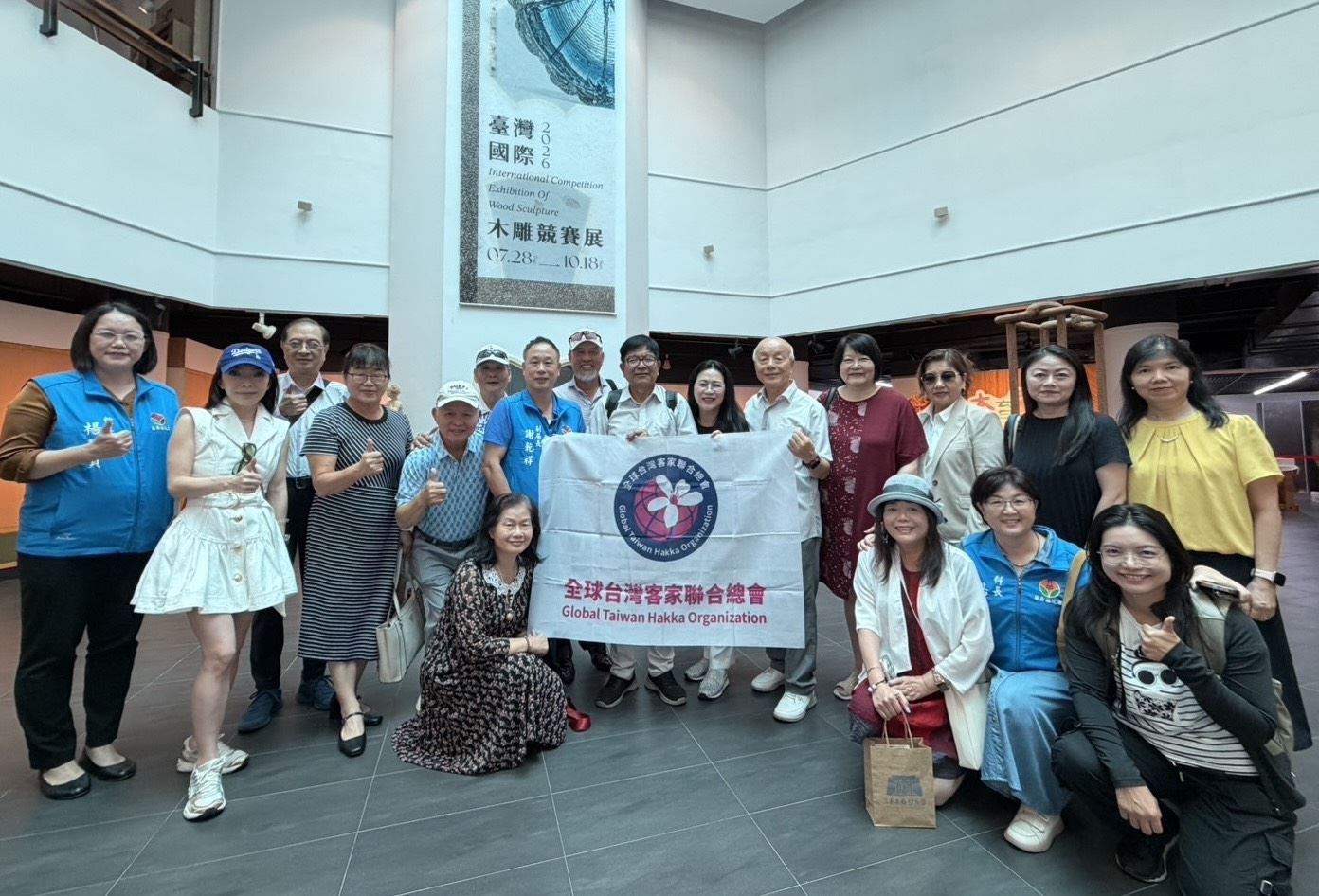 全球台灣客家聯合總會參訪團走訪三義木雕博物館，欣賞木雕藝術與在地工藝特色，並持總會旗幟合影留念。（圖／苗栗縣政府提供）