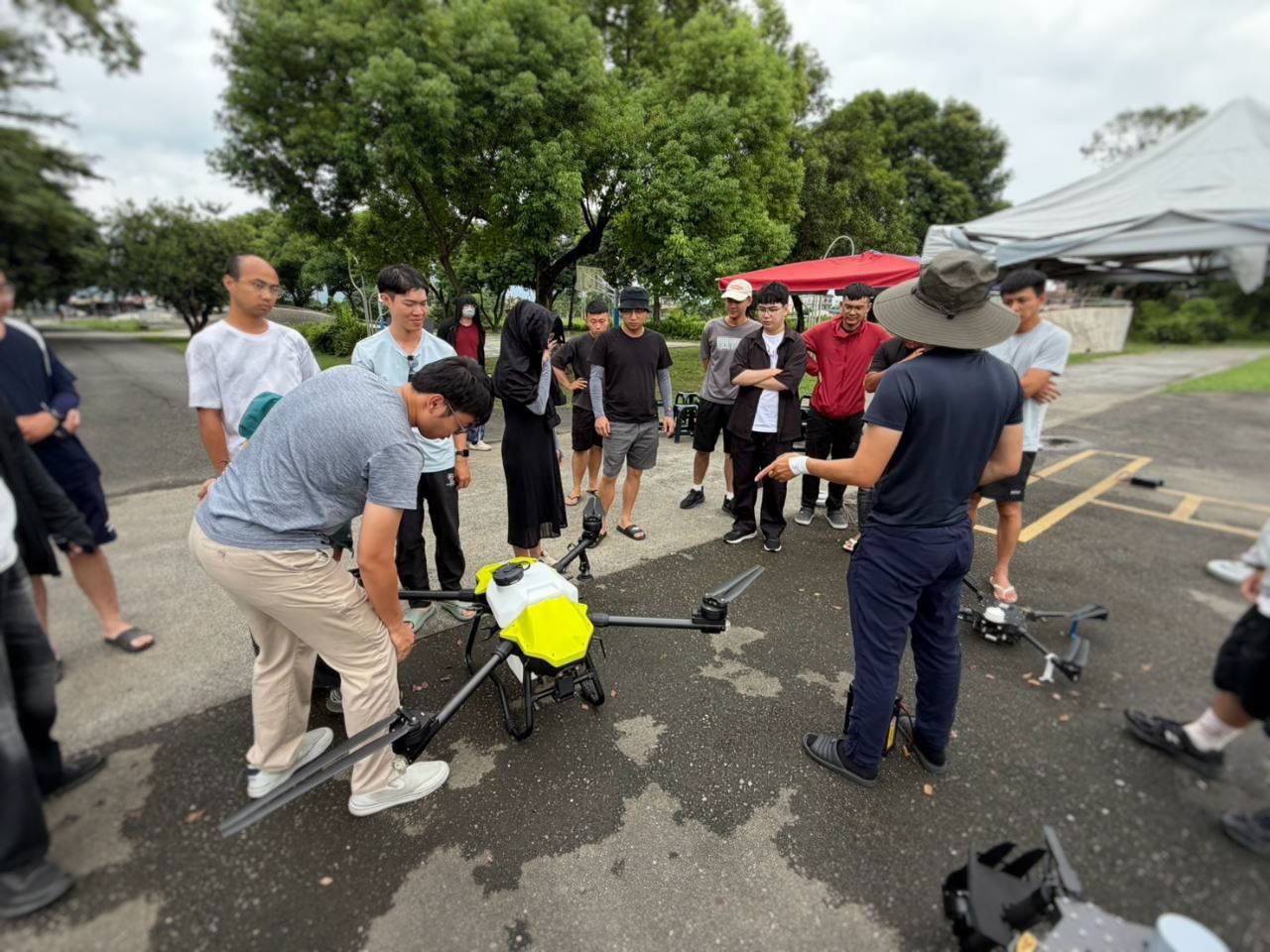 教練現場講解植保無人機構造與操作要點，屏東智慧農業學校學員近距離觀察設備，學習農業無人機實務技能。（圖／屏東縣政府提供）