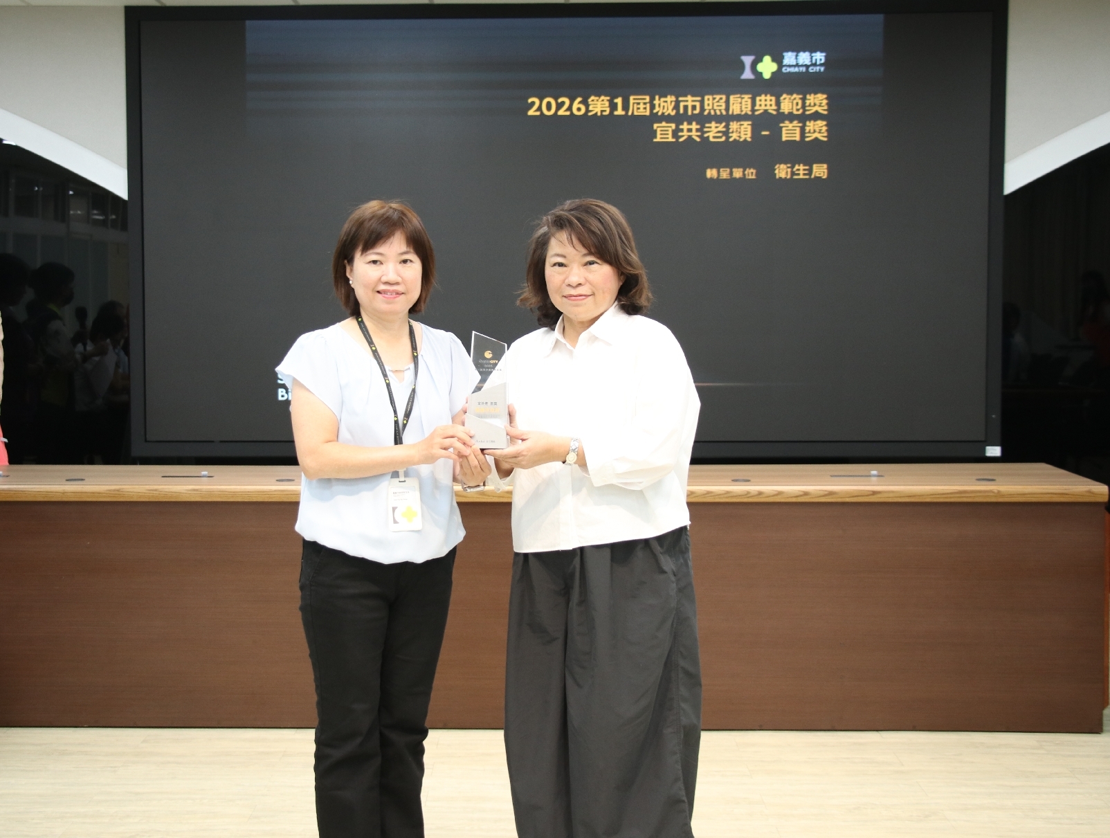 嘉義市「諸羅『醫』家長照親～一同共老」方案榮獲城市照顧典範獎「宜共老類－首獎」，衛生局長廖育瑋於市務會議將獎座轉呈市長黃敏惠，分享長照創新服務成果。（圖／嘉義市政府提供）